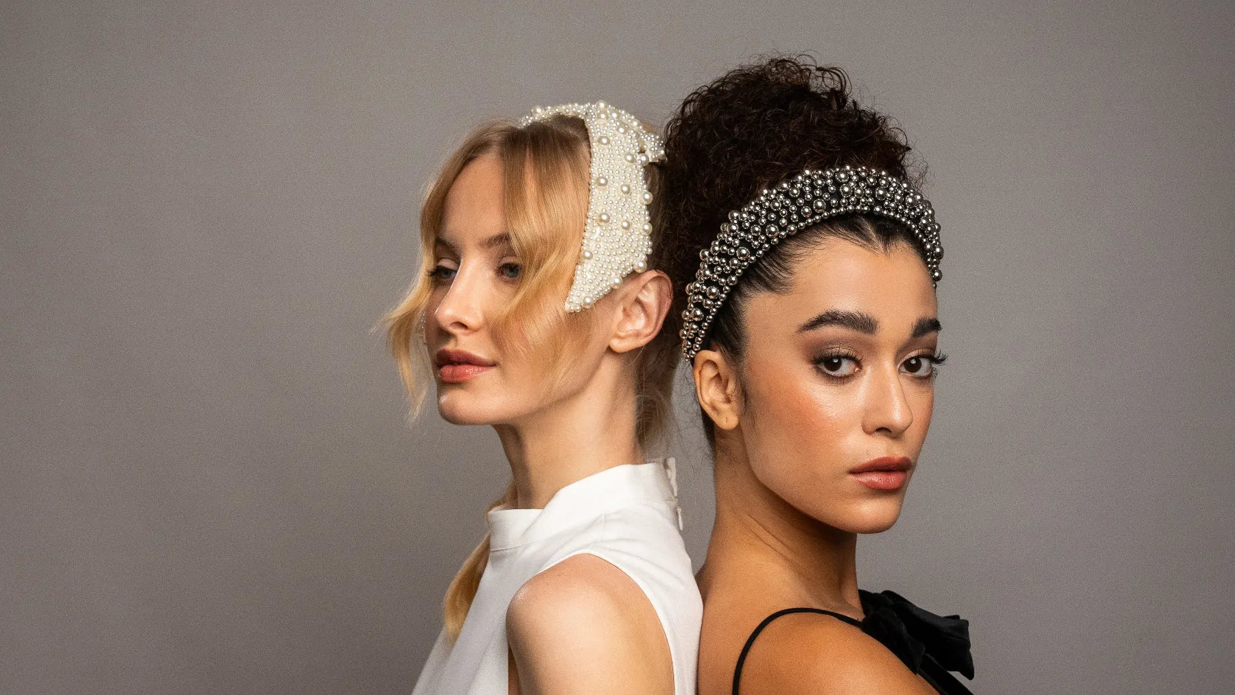 Two women wearing decorative headbands against a plain background