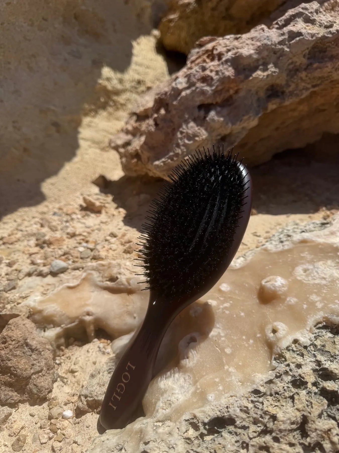 Burgundy hairbrush on a rocky surface