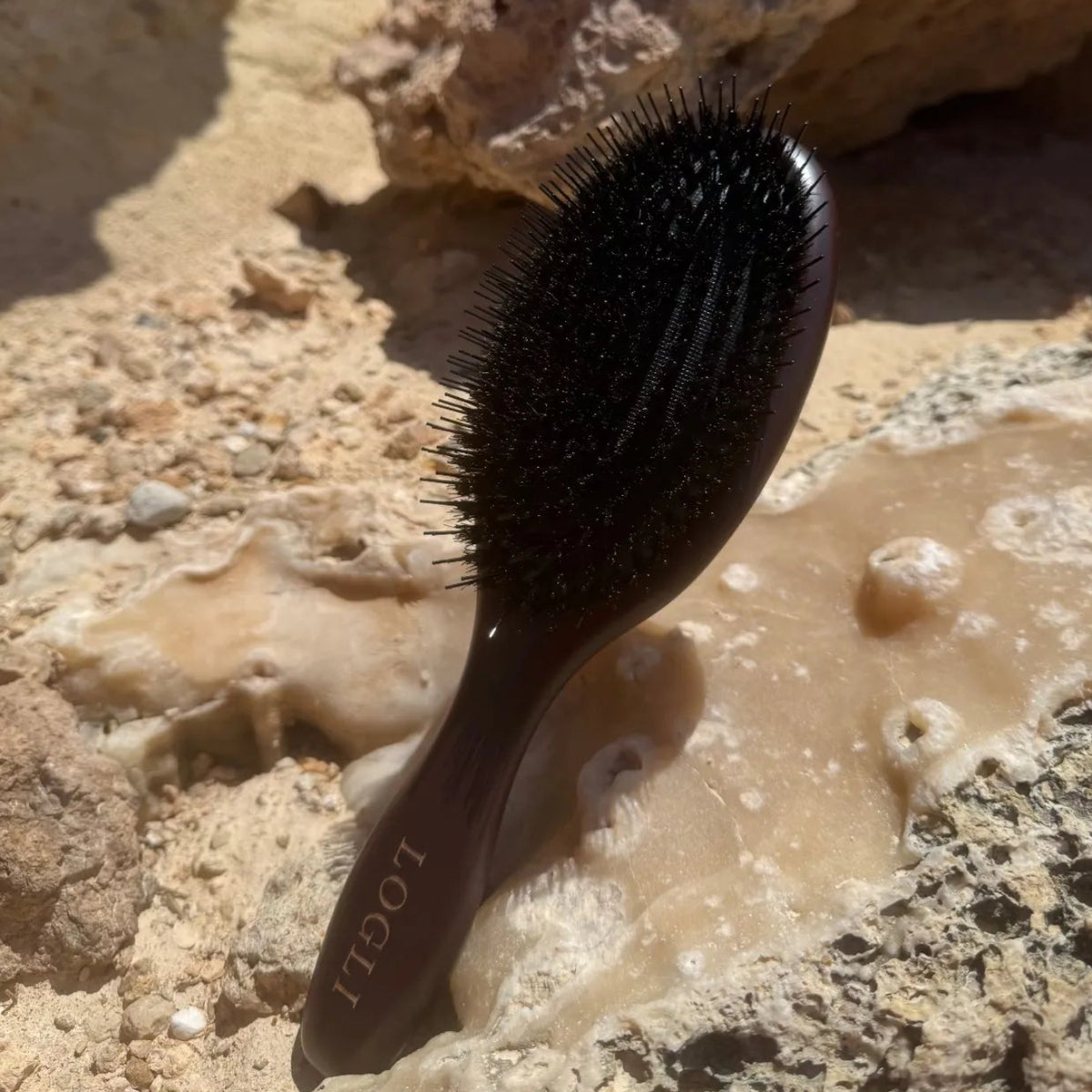 Burgundy hairbrush on a rocky surface