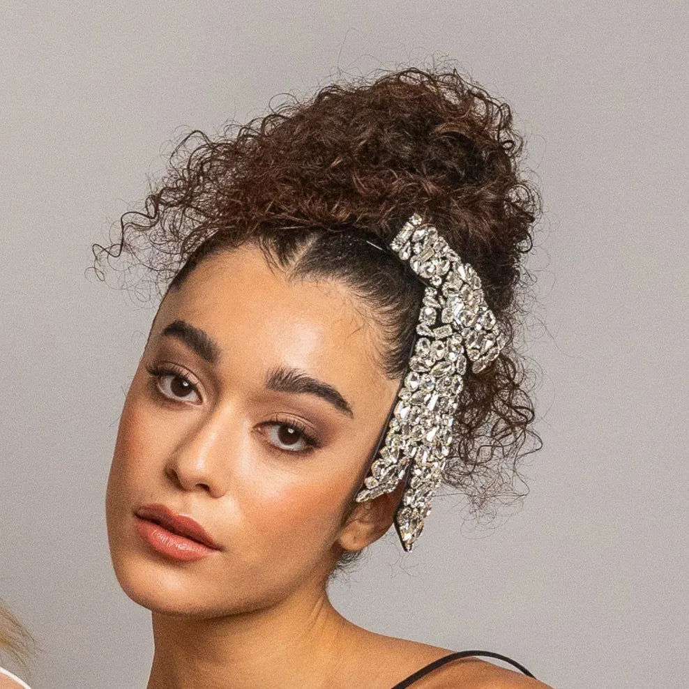 Woman with curly hair wearing a decorative headband against a gray background