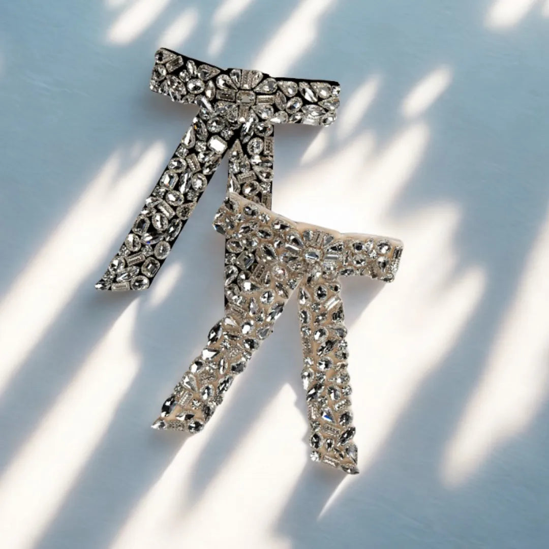 Silver bow-shaped brooch with rhinestones on a light background