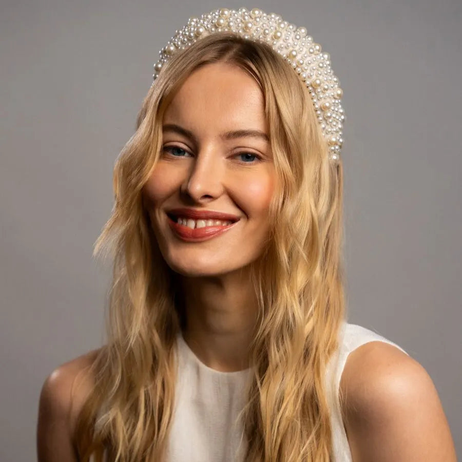Woman wearing a pearl headband against a gray background