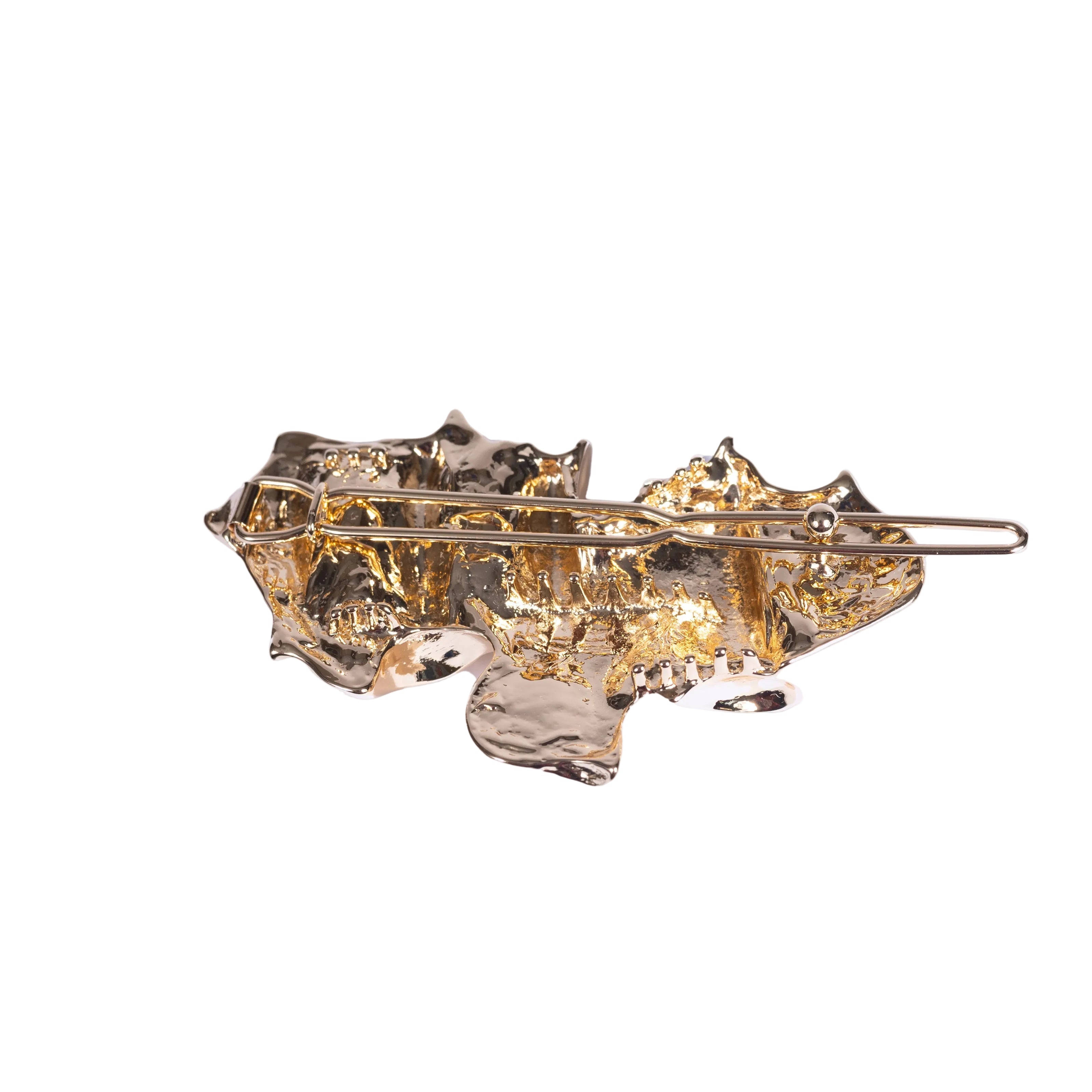 Gold clip with intricate design on a white background